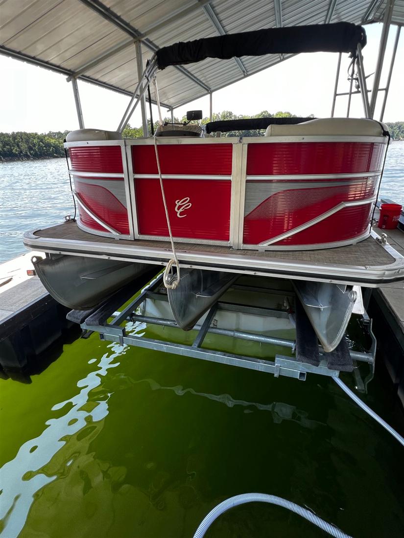 Red pontoon boat raised on an air boat lift in a covered slip