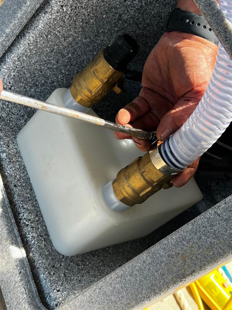 Technician connecting an air hose to a boat lift valve during a repair